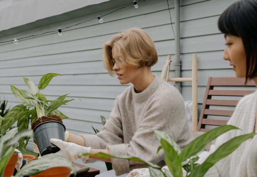 Woman gardener smiling while examining a healthy plant in a pot