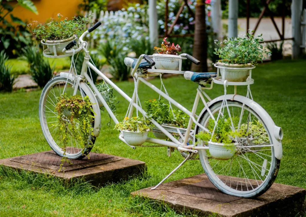 Upcycled white bicycle transformed into a planter overflowing with colorful flowers and greenery.