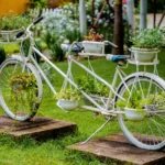 Upcycled white bicycle transformed into a planter overflowing with colorful flowers and greenery.