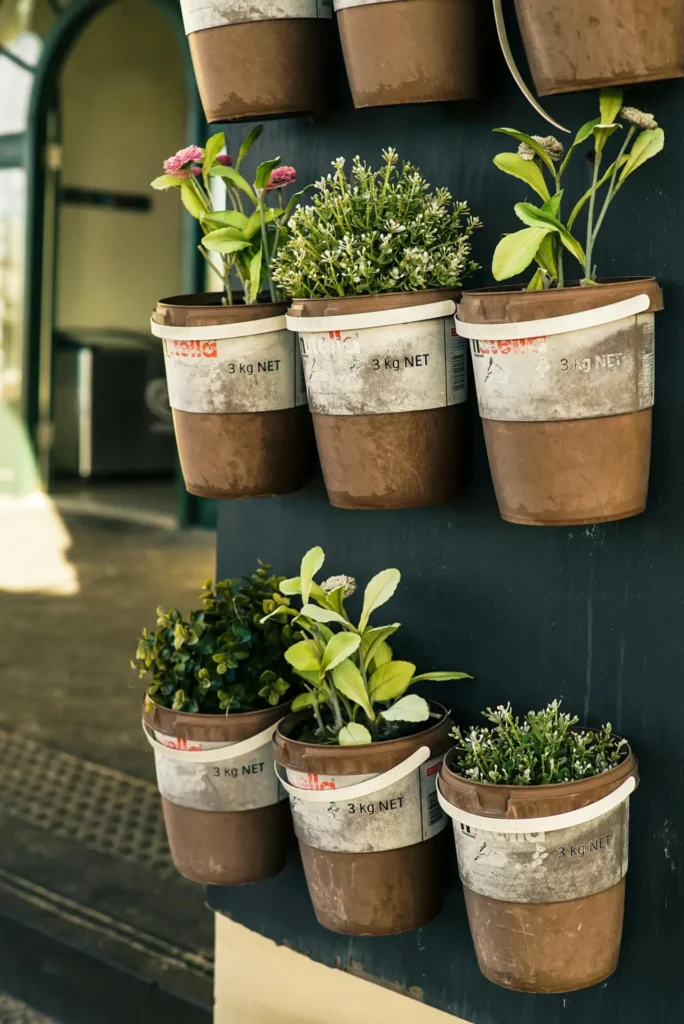 A vertical herb garden with multiple pockets overflowing with fresh herbs like basil, mint, and rosemary. The garden is hanging on a sunny wall.