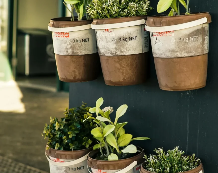 A vertical herb garden with multiple pockets overflowing with fresh herbs like basil, mint, and rosemary. The garden is hanging on a sunny wall.